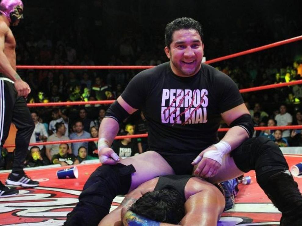 El Hijo del Perro Aguayo is smiling while sitting on an unconscious wrestler in the riing