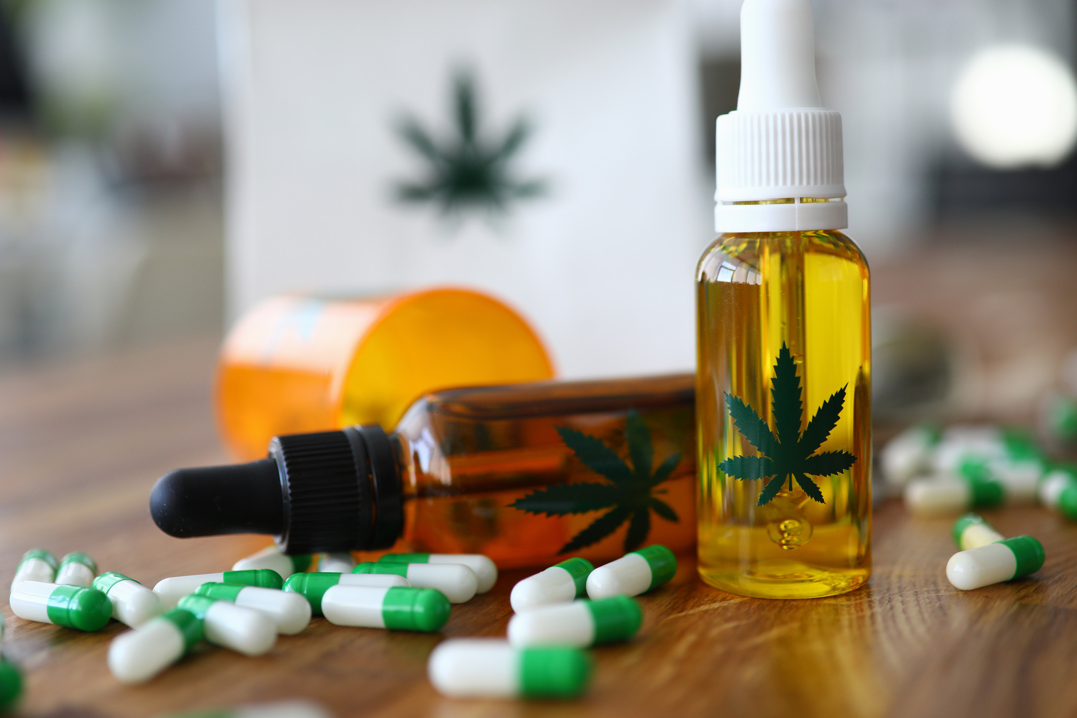 CBD drug bottles and green and white capsules on a wooden table