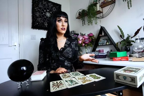 Jessica Caldwell wearing black clothing sitting in front of a tarot spread on a black table