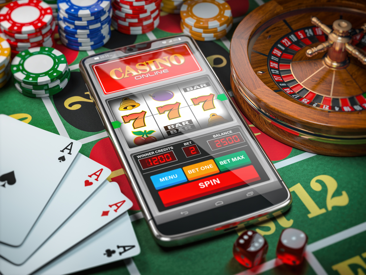 Cards, casino coins, roulette and a phone placed on a casino table