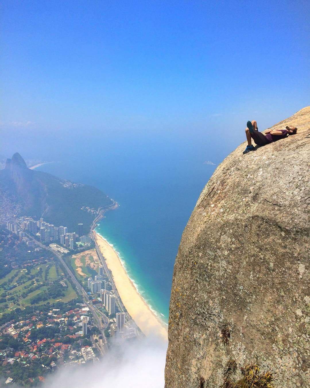 A man lying on Pedra De Gavea cliff