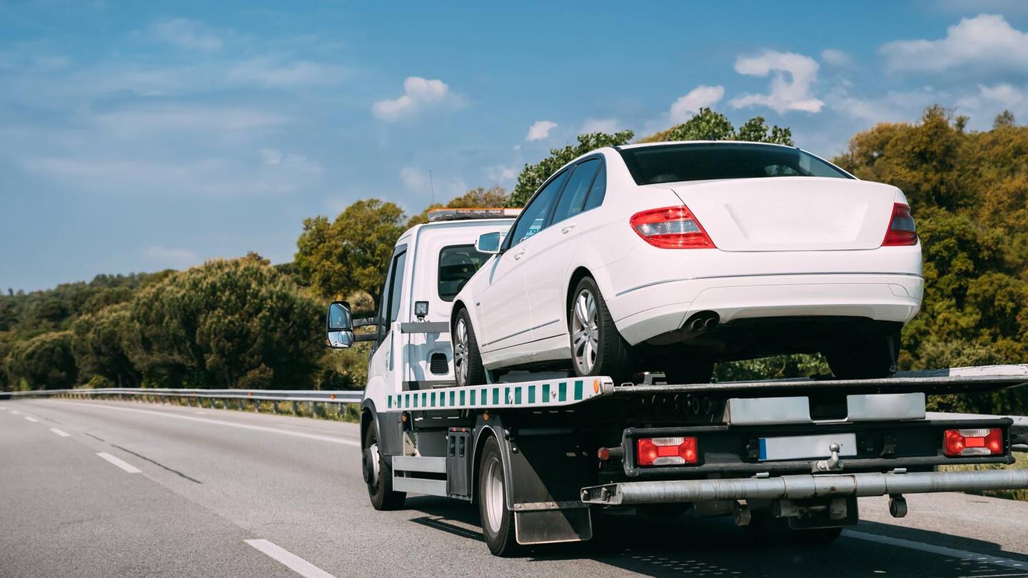 A tow truck carrying a white car