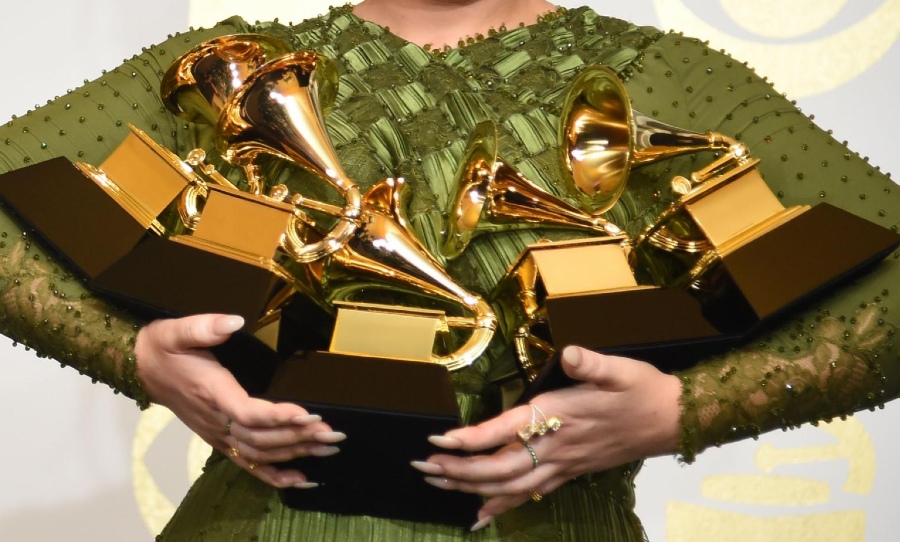 A woman holding five Grammy Awards