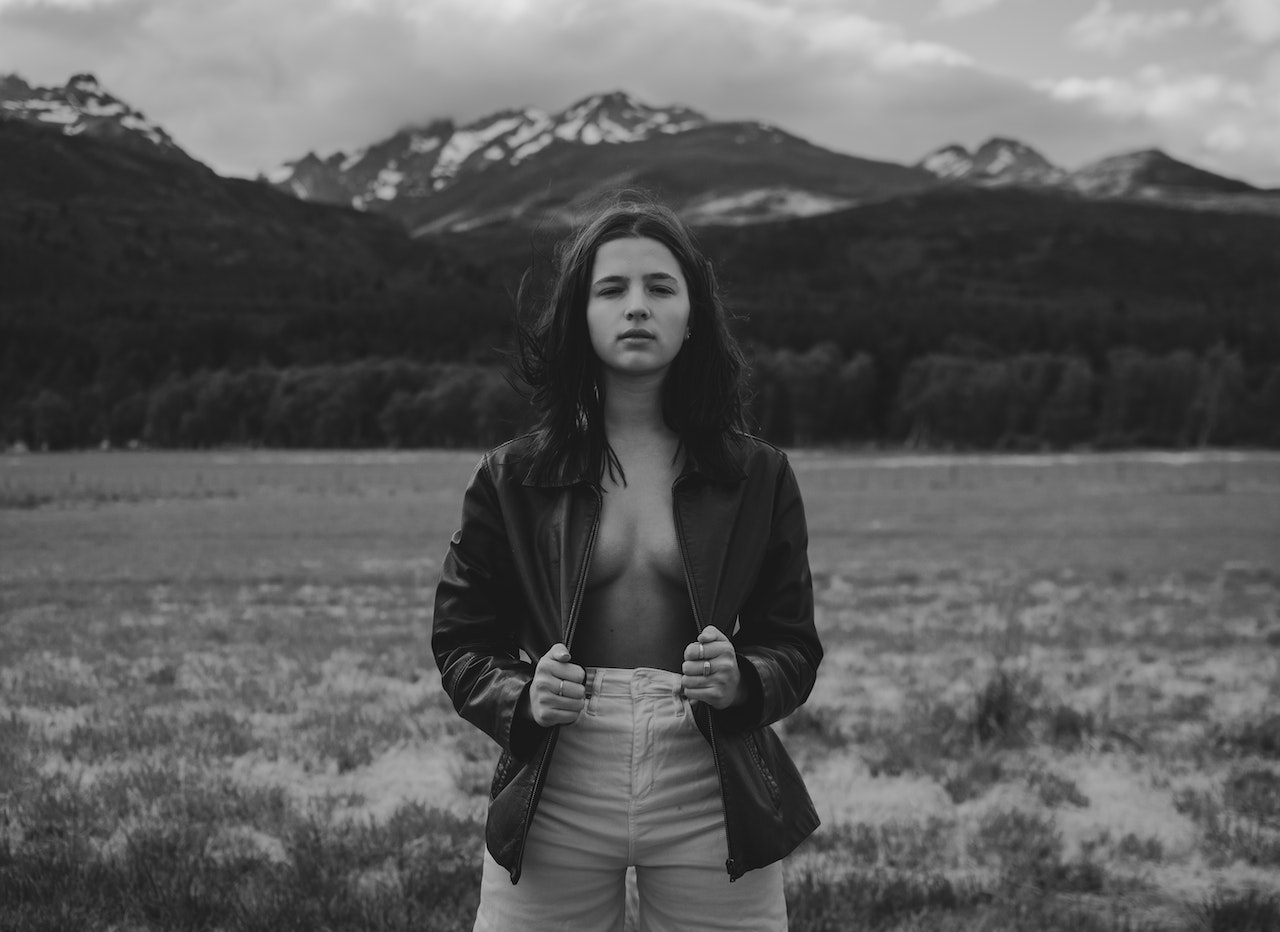 Self esteem young lady in leather jacket on naked body standing in highlands