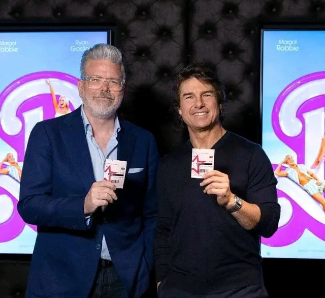 Christopher McQuarrie and Tom Cruise holding tickets for the Barbie movie.
