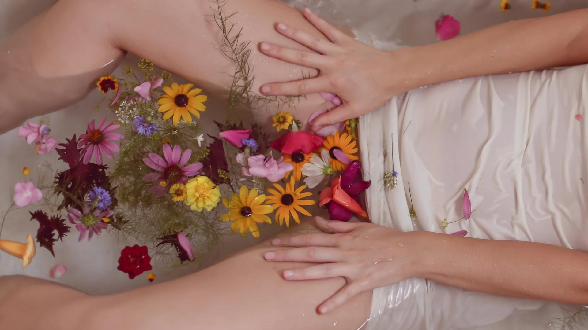A woman in the bath tub filled with different flowers