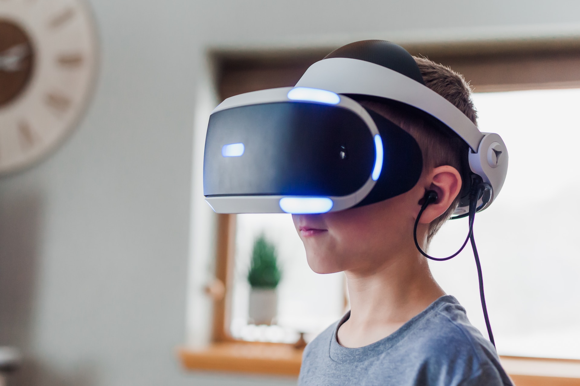 A male kid in T-shirt and wearing a virtual reality headset for a VR gameplay