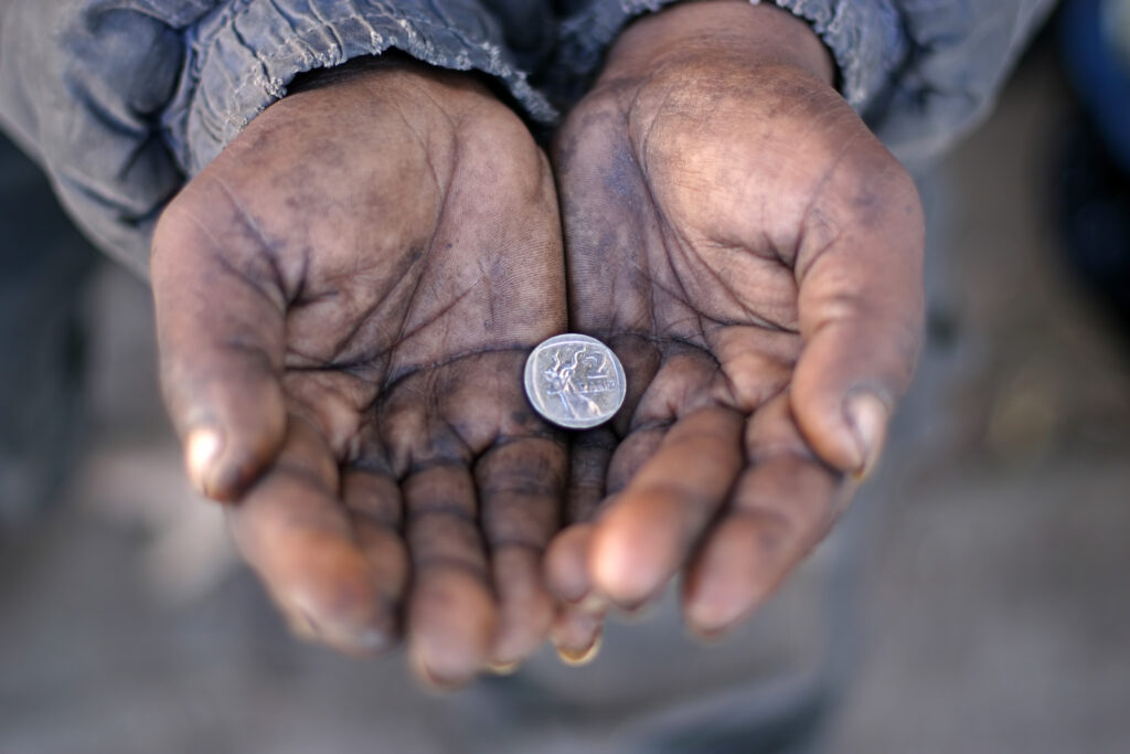 A person's open hand with one silver coin.