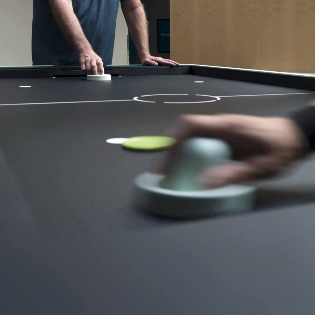 Two persons playing on black-base air hockey table