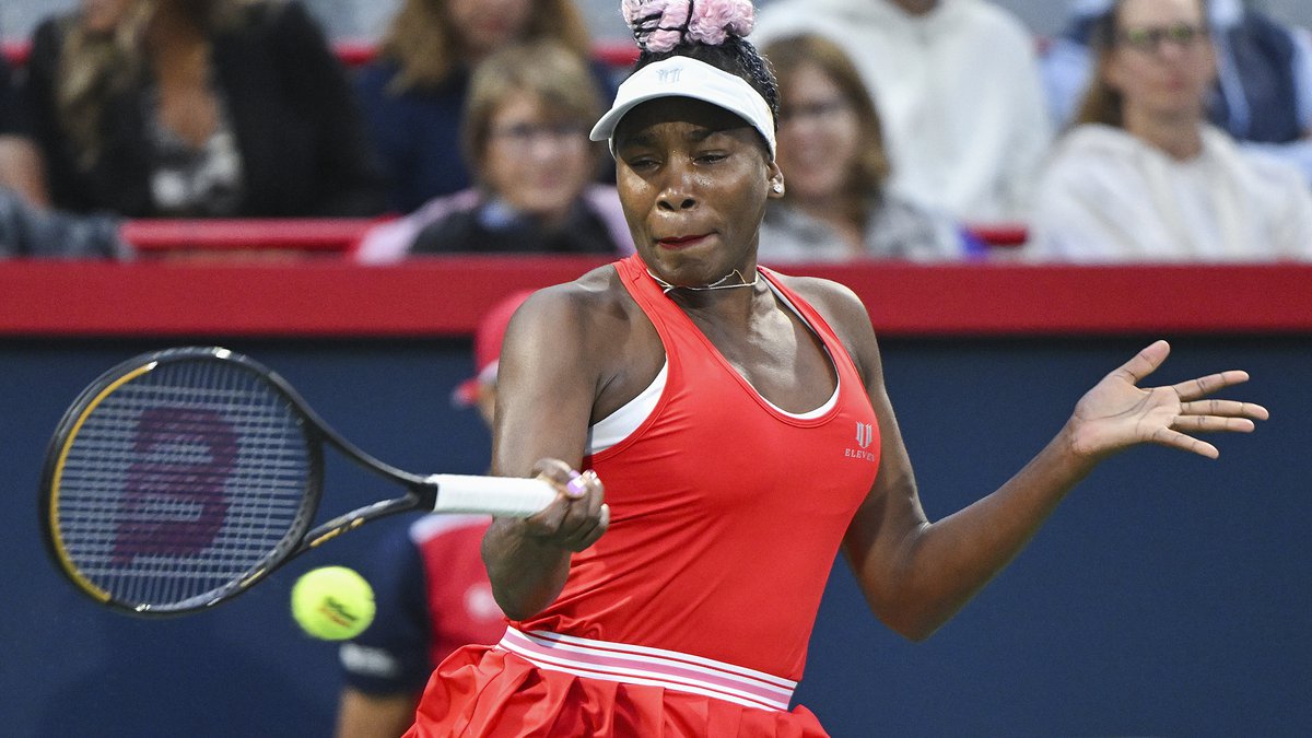 Venus Williams wearing a red sports dress wjile holding a tennis racket