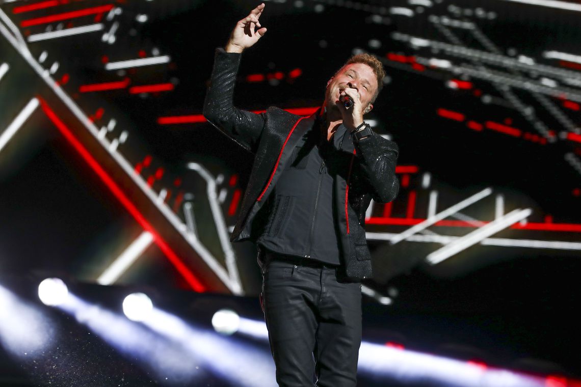Brian Littrell wearing a black leather jacket while holding a mic
