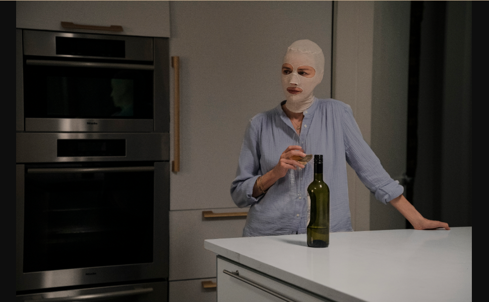 The mother holding a glass of wine with the bottle sitting on a kitchen table