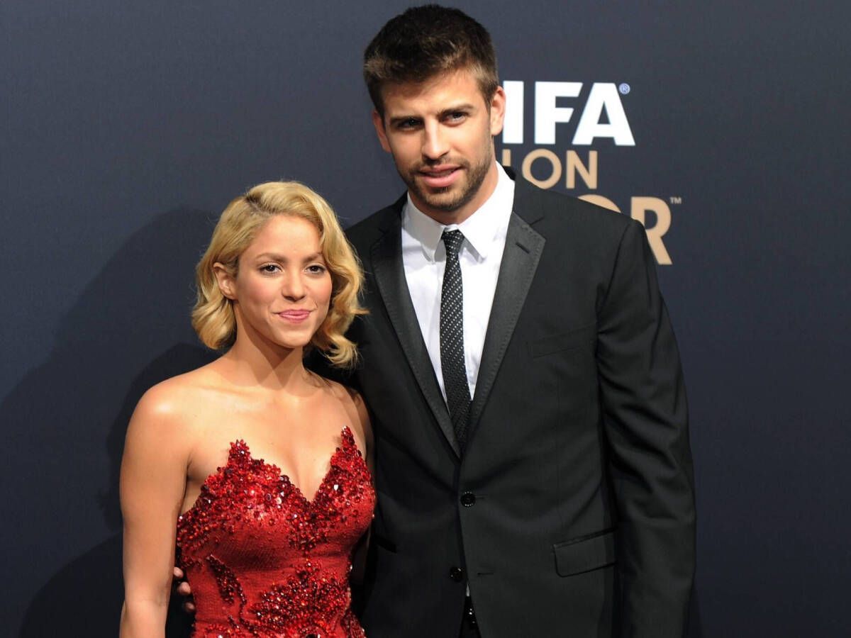 Shakira wearing a red dress and Gerard Pique wearing a black suit