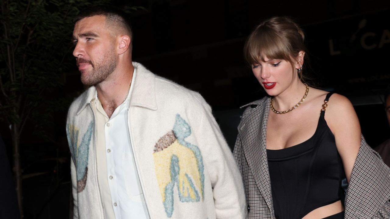 Travis Kelce wearing a white Jacket and taylor Swift wearing black and white coat