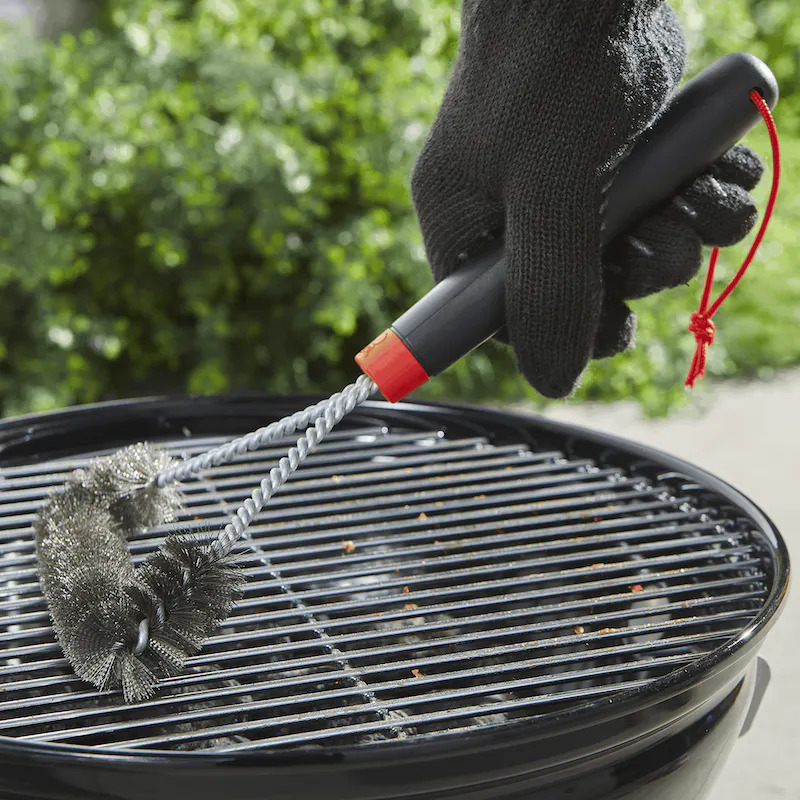 Person cleaning grill with grill brush.
