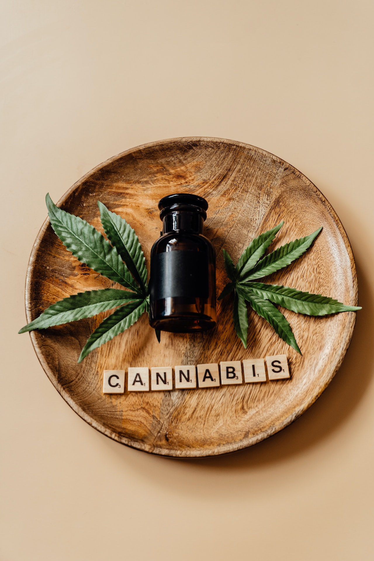 Wooden plate labeled as Cannabis has hepm leaves and glass bottle.