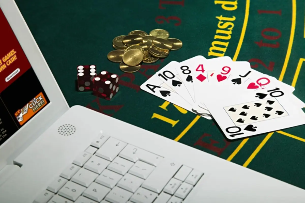 Laptop, cards and coins in casino for gambling