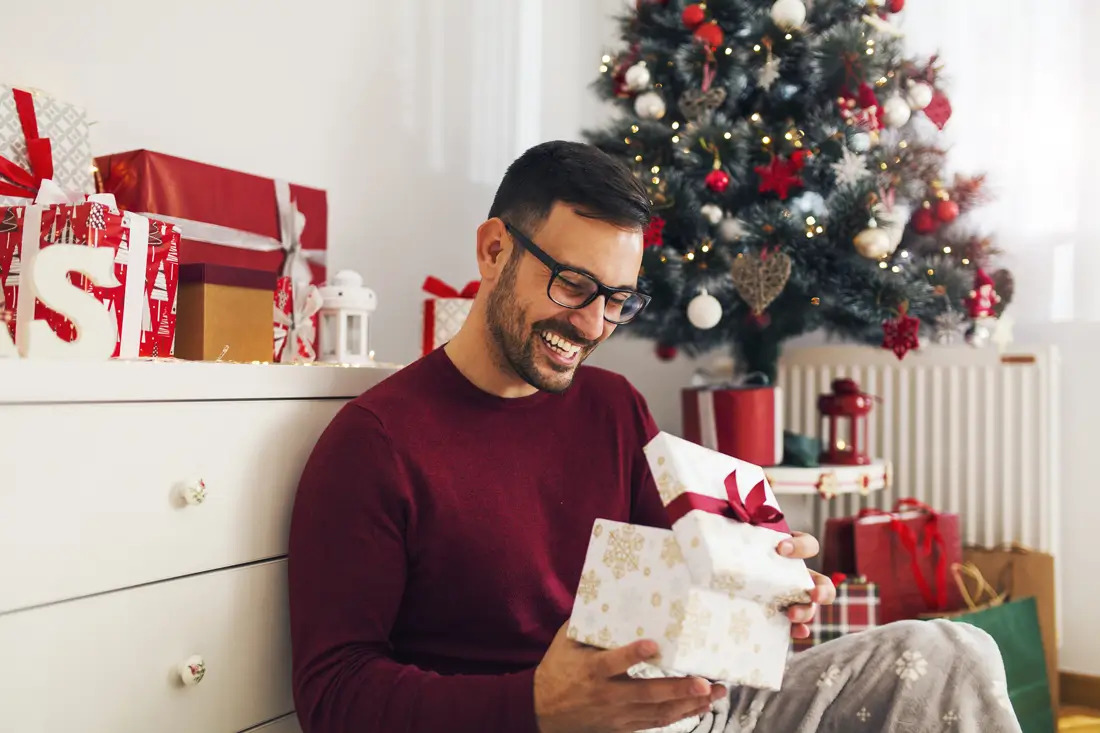 Smiling man holding gifts.