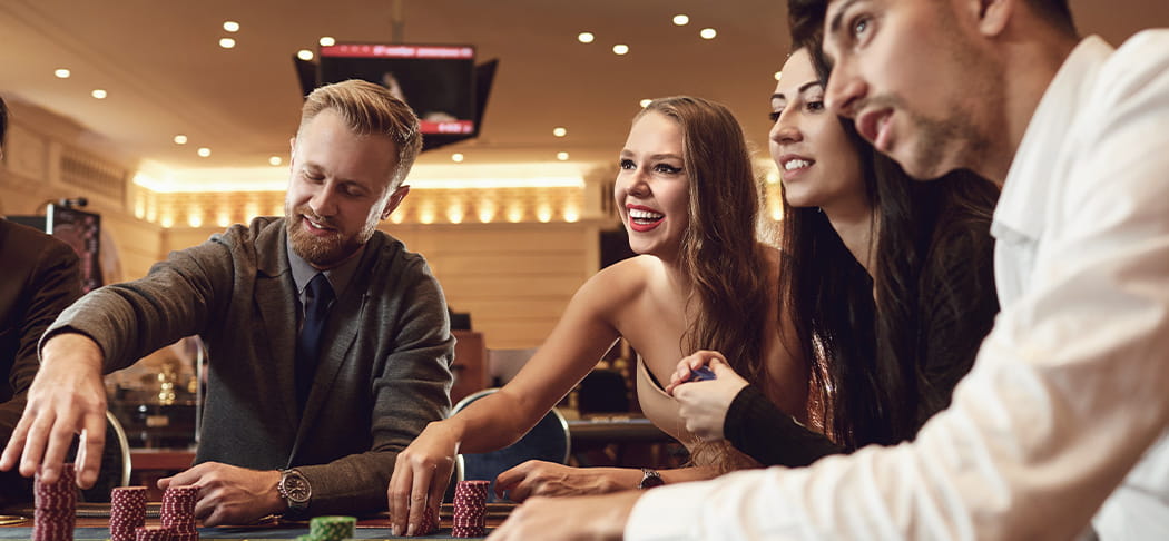 Two men and two women are playing in casino.