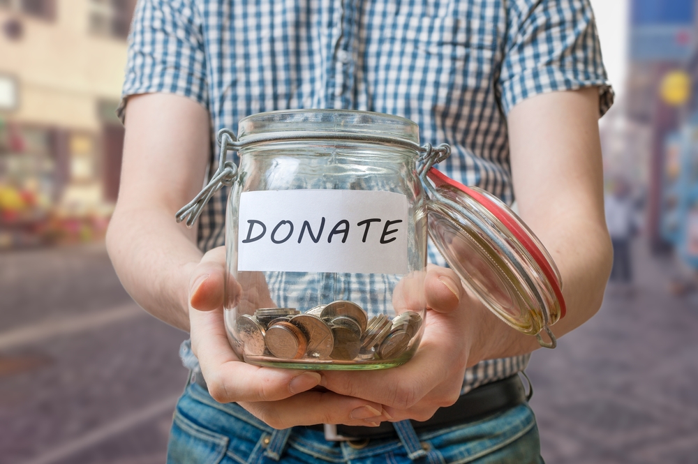 A boy is holding a donation jar